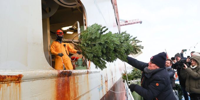 Eine Sponsorin wirft einen Weihnachtsbaum zu zwei Seeleuten in die Luke eines Containerschiffes im Hamburger Hafen. Eine Sponsorin wirft einen Weihnachtsbaum zu zwei Seeleuten in die Luke eines Containerschiffes im Hamburger Hafen.