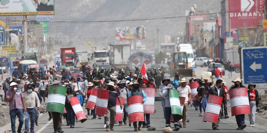 Demonstranten marschieren bei einem Protest gegen die Regierung von Präsidentin Boluarte mit behelfsmässigen Schildern über eine Strasse im peruanischen Arequipa.