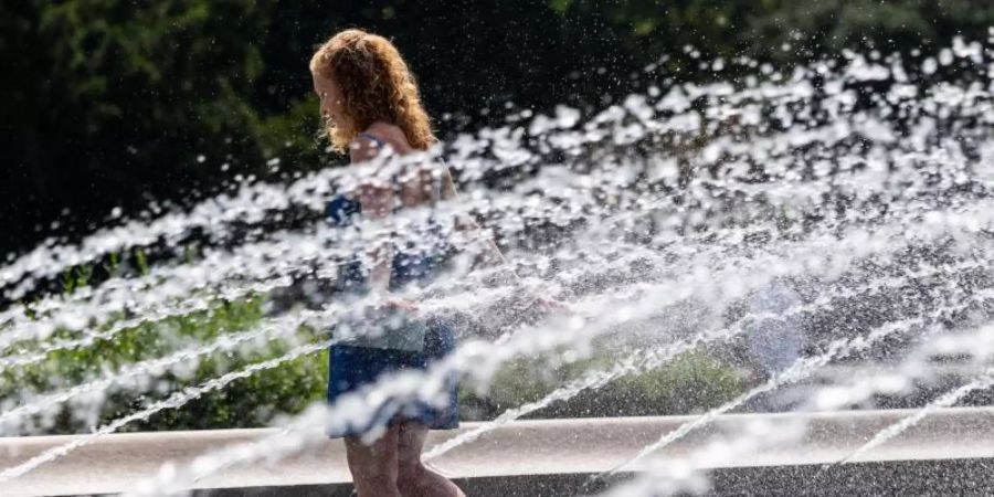 Die junge Frau aus Dresden läuft durch einen Brunnen am Albertplatz um sich abzukühlen. Foto: Robert Michael