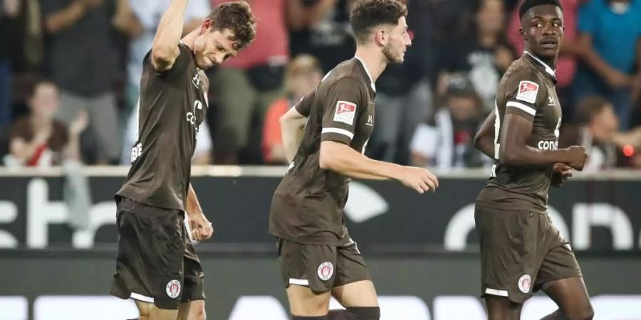 St. Paulis James Lawrence (l-r), Matt Penney und Christian Conteh feiern das Tor zum 1:0 gegen Holstein Kiel. Foto: Christian Charisius