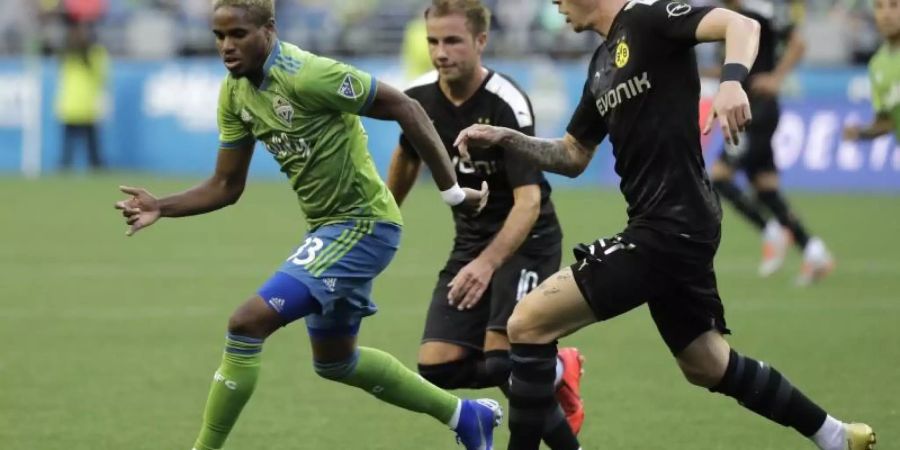 Joevin Jones von den Seaattle Sounders (l) wird von den BVB-Spielern Marius Wolf (r) und Mario Götze attackiert. Foto: Ted S. Warren/AP