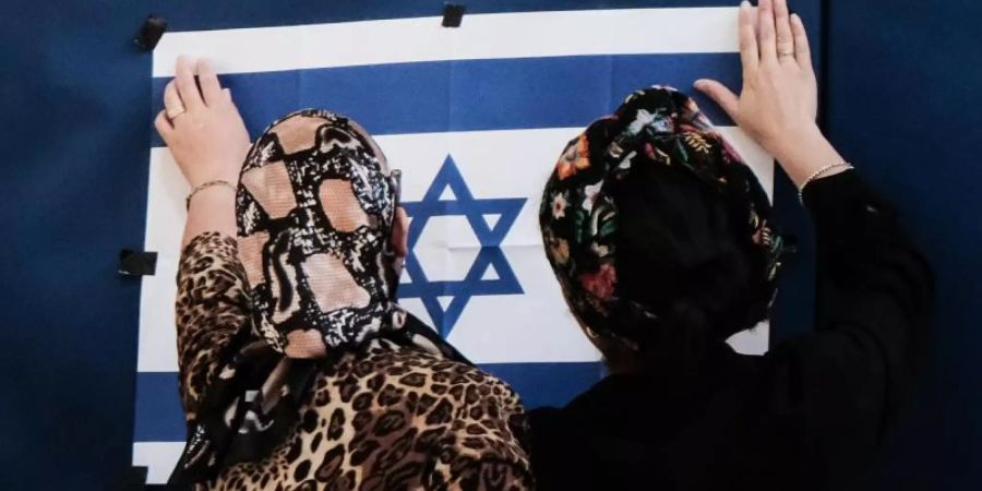 Zwei Mitarbeiterinnen des Wahlausschusses befestigen in einem Wahllokal in Jerusalem eine israelische Fahne. Foto: Nir Alon/ZUMA Wire