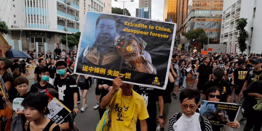 Ein Demonstrant hält bei einer Kundgebung ein Plakat mit einem Bild des chinesischen Präsidenten Xi mit einer Uniform aus den «Avenger»-Filmen und der Aufschrift «Ausliefern nach China, verschwinde für immer» in die Höhe.