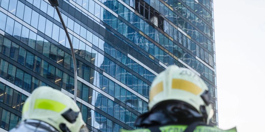 Feuerwehrleute stehen neben dem beschädigten Hochhaus im Geschäftsviertel Moskwa City.