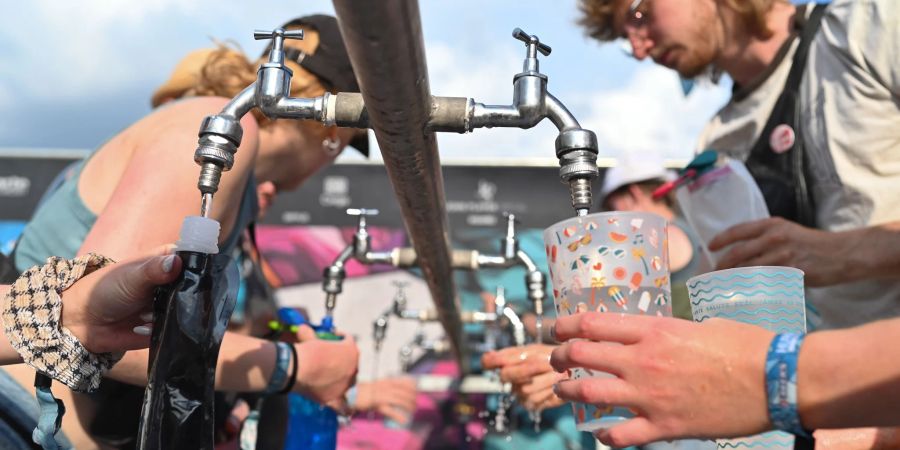 Besucher füllen beim Hurricane Festival ihre Becher und Trinkflaschen mit Wasser auf. In Deutschland steigen die Temperaturen - und die Ozon-Werte.