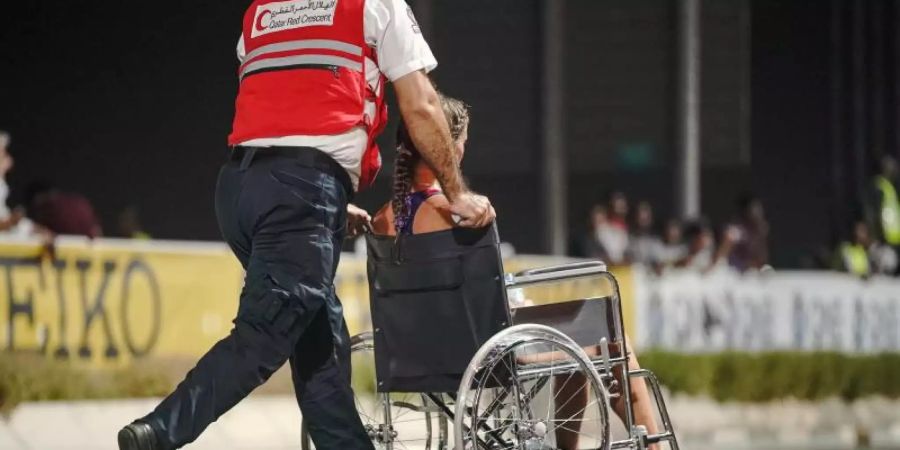 Nur 40 der 68 gestarteten Teilnehmerinnen kamen beim Marathon in Doha ins Ziel: Ein Sanitäter bringt eine erschöpfte Läuferin von der Strecke. Foto: Michael Kappeler