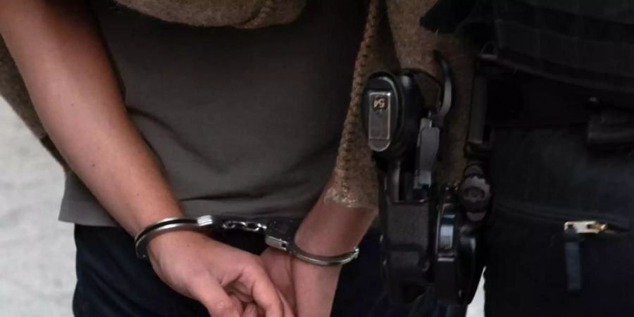 Polizisten führen nach einer Razzia einen verdächtigen Mann ab. Foto: Paul Zinken/dpa