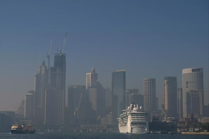 Ein Kreuzfahrtschiff liegt vor der verrauchten Skyline Sydneys im Hafen. Buschbrände in Australien