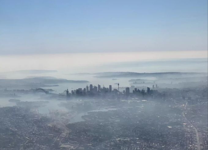 Auf dem mit einem Smartphone durch ein Flugzeugfenster aufgenommenen Foto liegen Rauchschleier über der Skyline von Sydney. Wegen der Buschbrände in der Umgebung von Sydney wird die Lage auch in Australiens Millionenmetropole selbst zunehmend bedrohlich. Über der Stadt hing am Dienstag ein dicker Rauchschleier. Sydney Feuer