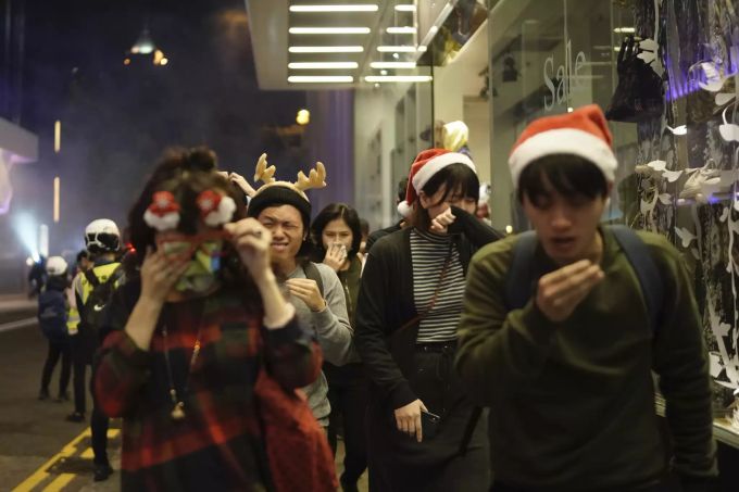 Weihnachtlich gekleidete Passanten bekommen Tränengas ab, welches gegen die Demonstranten eingesetzt wird. Hong Kong Protests