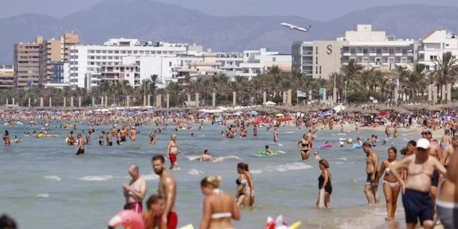 Touristen sonnen sich am Strand von El Arenal, einem der Hauptziele für deutsche und niederländische Touristen während der Sommersaison auf der Balearen-Insel Mallorca. Foto: Clara Margais/dpa
