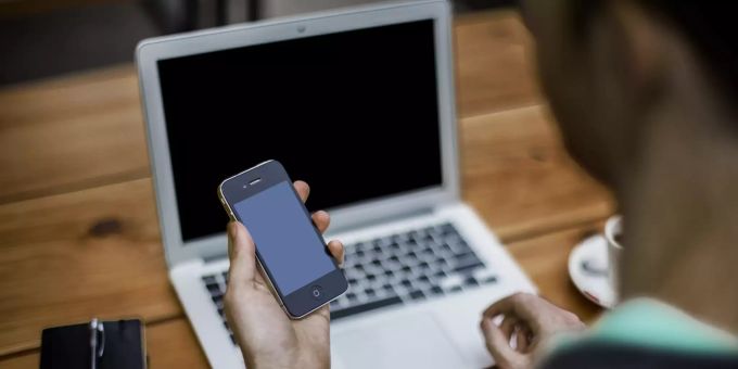 Ein Mann blickt auf sein iPhone. 8chan 8kun iphone Mann