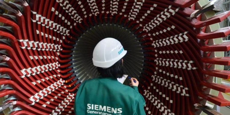 Eine Frau betrachtet einen Generatorständer im Siemens-Generatorenwerk in Erfurt. Foto: Martin Schutt