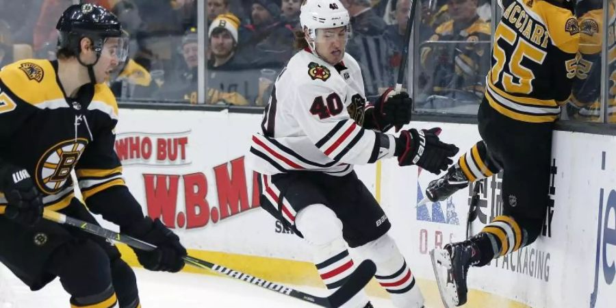 John Hayden (M) von den Chicago Blackhawks kämpft gegen zwei Spieler der Boston Bruins um den Puck. Foto: Michael Dwyer/AP