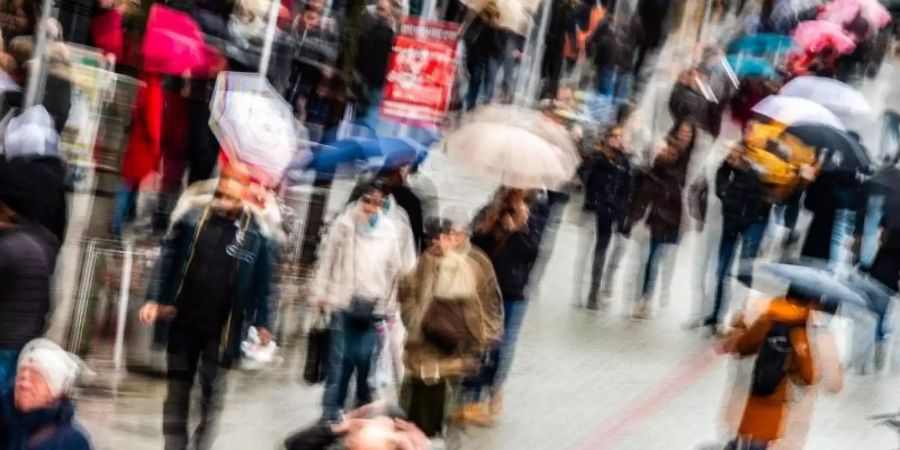 Passanten mit Einkaufstüten gehen durch eine Fussgängerzone. Foto: Swen Pförtner/Illustration