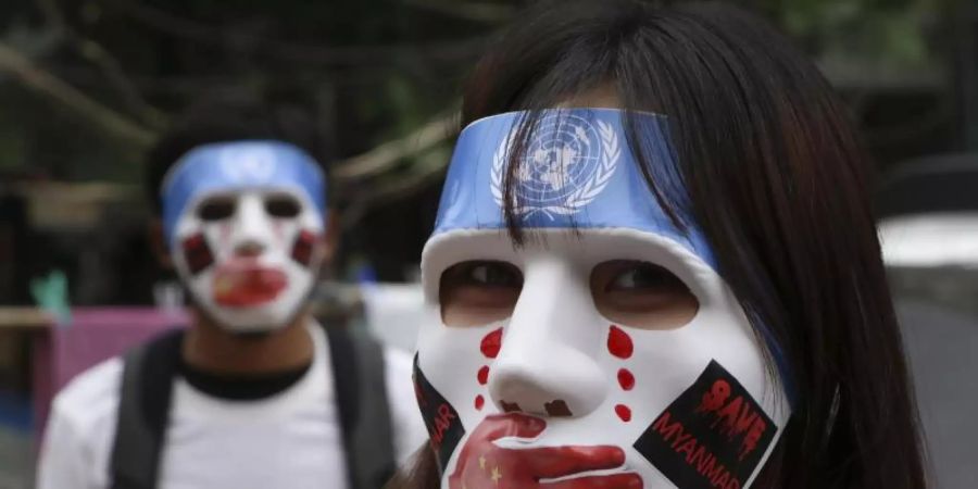 Junge Demonstranten in Yangon tragen Masken, auf denen das Logo der Vereinten Nationen, eine rote Hand über dem Mund, rote Tränen und Aufkleber mit der Aufschrift «Save Myanmar» zu sehen sind. Foto: Uncredited/AP/dpa