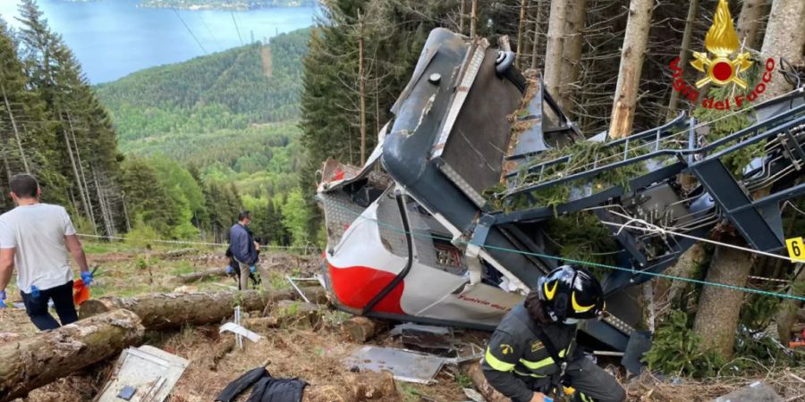 HANDOUT - Rettungshelfer arbeiten am Wrack einer Seilbahngondel, nachdem diese abgestürzt ist. Nach dem Gondelunglück in Norditalien vom Sonntag mit 14 Toten sind Medienberichten zufolge drei Menschen festgenommen worden. Foto: Uncredited/Vigili del Fuoco Firefighters/AP/dpa - ACHTUNG: Nur zur redaktionellen Verwendung im Zusammenhang mit der aktuellen Berichterstattung und nur mit vollständiger Nennung des vorstehenden Credits