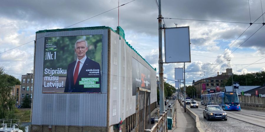 Ein Wahlplakat der liberalkonservativen Regierungspartei mit einem Porträt von Ministerpräsident Krisjanis Karins hängt an einer Hauswand in der Hauptstadt Riga.