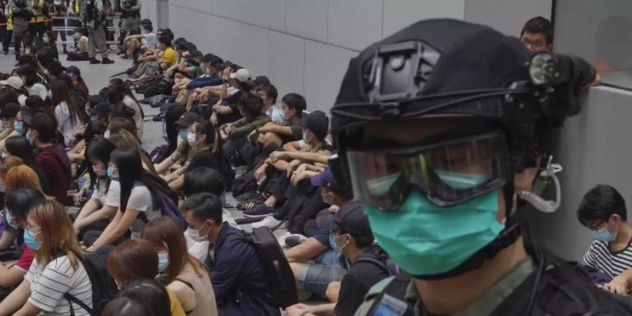 Von Bereitschaftspolizisten festgehaltene regierungskritische Demonstranten im Zentrum von Hongkong. Foto: Vincent Yu/AP/dpa