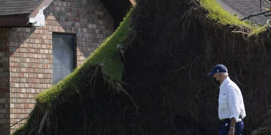 US-Präsident Joe Biden läuft an einem grossen entwurzelten Baum vorbei, als er in LaPlace, Louisiana, selbst ein Bild von den Sturmschäden macht. Foto: Evan Vucci/AP/dpa