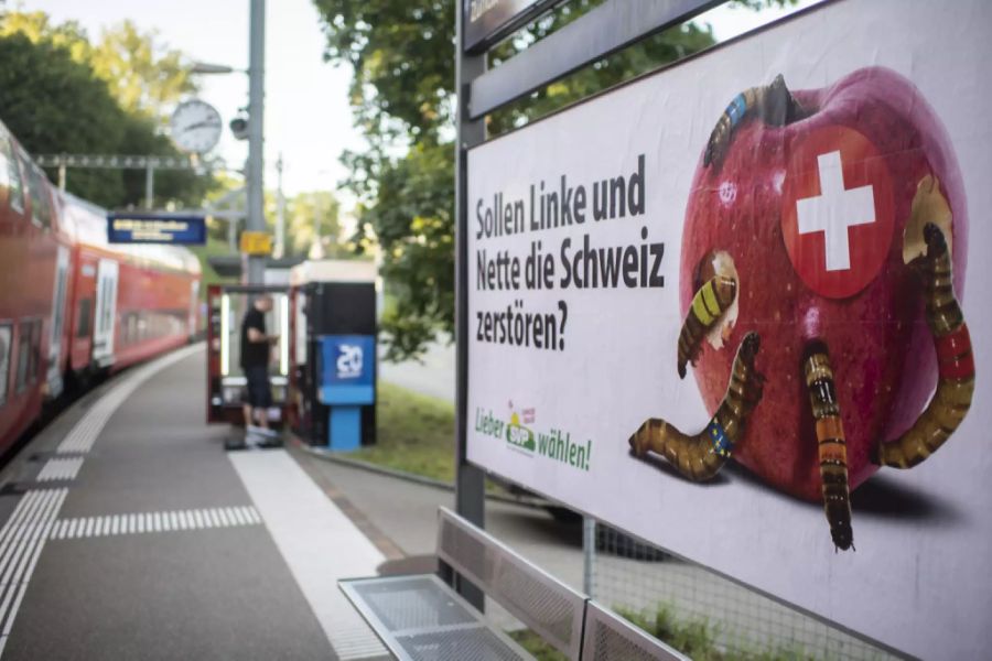 Wahlplakat der SVP mit der Schweiz als Apfel und Würmern, die die anderen Parteien symbolisieren, aufgenommen an der Haltestelle Brunau der SZU, am 26. August 2019 in Zürich.