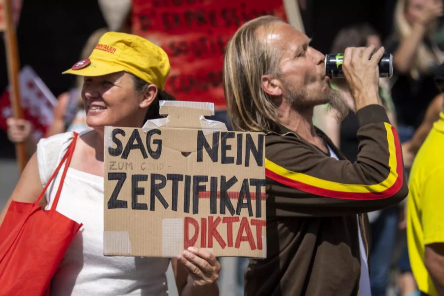 Protestler weibeln mit einem Plakat gegen das Covid-Zertifikat.