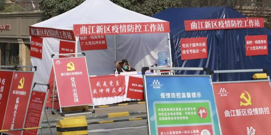 Eine Mitarbeiterin der Regierung an einem Kontrollpunkt vor einem Wohnblock in der Stadt Xi'an. Foto: Uncredited/CHINATOPIX/AP/dpa