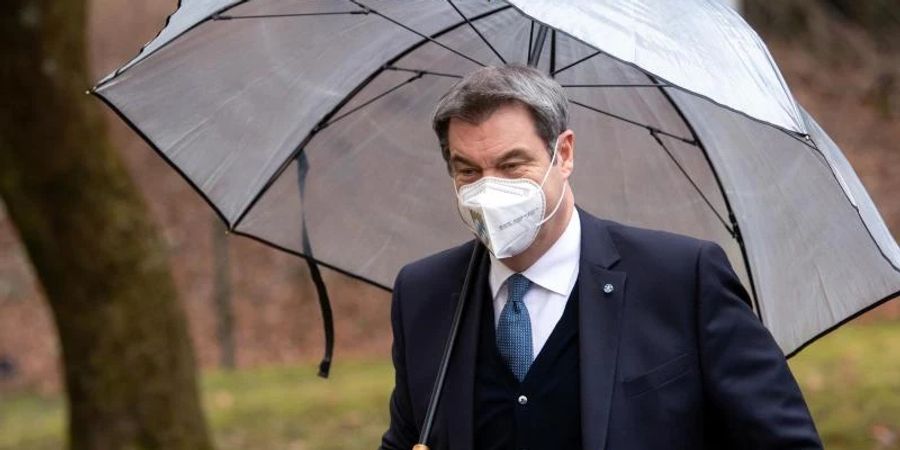 Markus Söder (CSU), Ministerpräsident von Bayern, kommt unter einem Regenschirm zur Pressekonferenz nach der Kabinettssitzung. Foto: Sven Hoppe/dpa