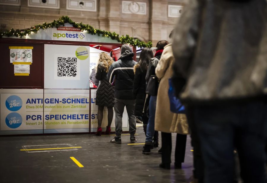 Personen stehen in der Warteschlange für einen Covid-19 Coronavirus Antigen-Schnelltest oder PCR-Speicheltest bei einem Testzentrum in der grossen Halle des Zürcher Hauptbahnhofs, am Freitag, 17. Dezember 2021 in Zürich.