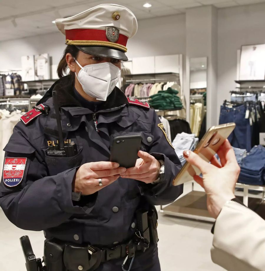 Eine Beamte der Kärntner Polizei kontrolliert am Dienstag 11. Januar ein Covid-Zertifikat in einem Geschäft.