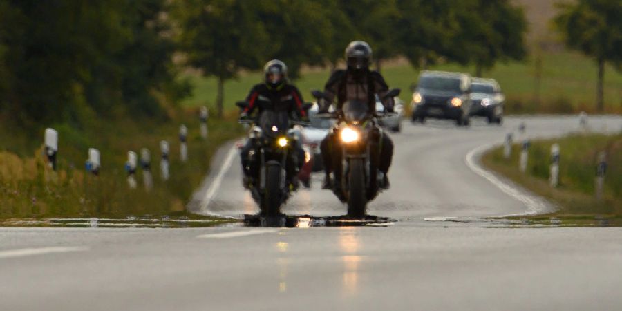 Zwei Biker fahren auf einer Landstrasse.