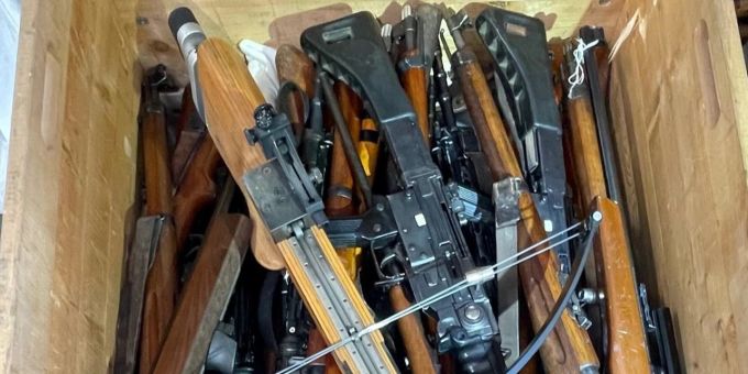 Holzkiste mit abgegebenen Karabinern und einer Armbrust Holzkiste mit abgegebenen Karabinern und einer Armbrust