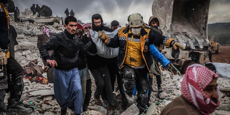 Zivilisten und Mitglieder des syrischen Zivilschutzes führen Such- und Rettungsmassnahmesuchen in den Trümmern eines zerstörten Gebäudes durch. Foto: Anas Alkharboutli/dpa