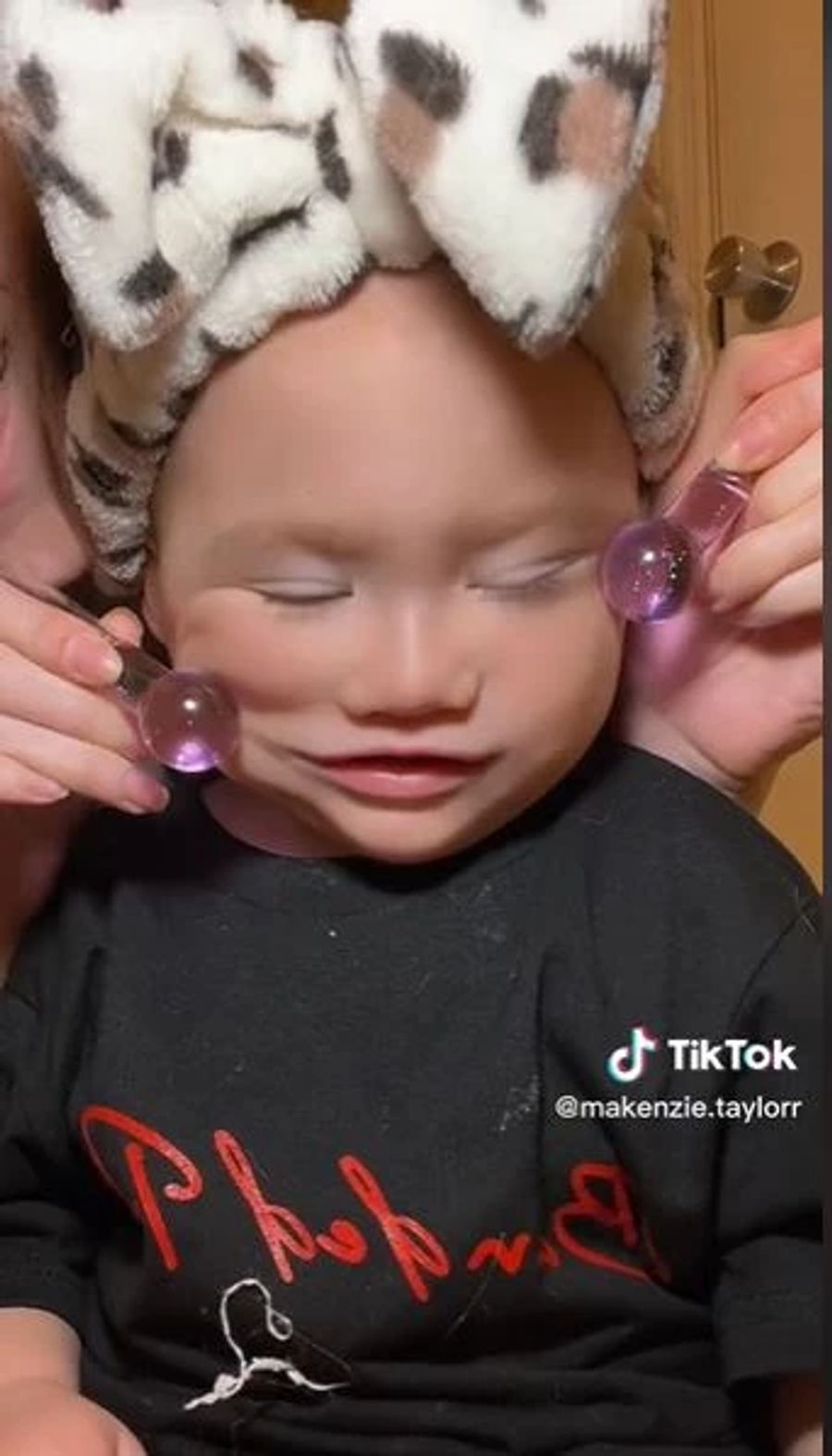 Die Mutter massiert das Gesichtchen der Tochter mit Eiskugeln aus Plastik.