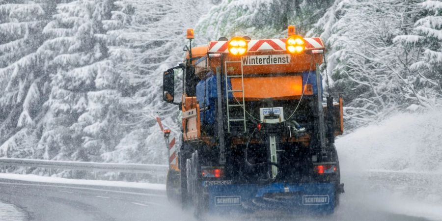 Ein Fahrzeug des Winterdiensts fährt durch eine verschneite Landschaft in Thüringen.