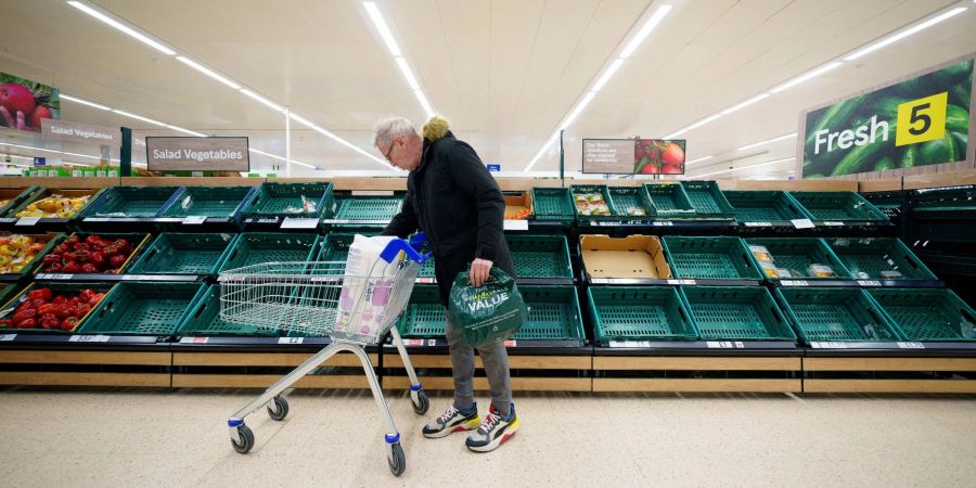 Ein Mann steht vor einem leeren Gemüseregal in einem Supermarkt in Manchester.