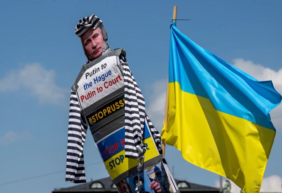 09.05.2022, Bayern, München: Demonstranten mit einer Puppe mit dem Bild des russischen Präsidenten Putin und der Aufschrift «Putin to the Hague - Putin to Court» protestieren am Odeonsplatz