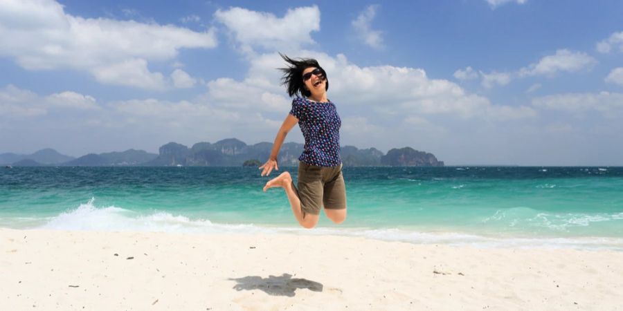 Frau Sprung Strand Meer im Hintergrund Freude