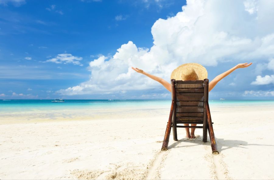 Frau sitzt am Strand.