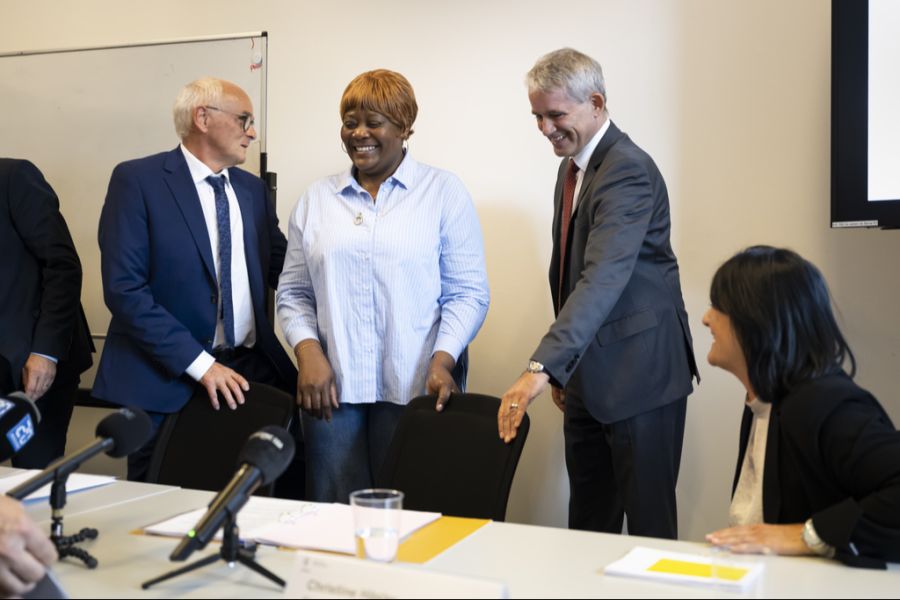 Bundesrat Beat Jans und Regierungsrat Pierre Alain Schnegg bieten der aus dem Kongo geflüchteteten Andrea-Frida Mayala ihren Platz an, während der Medienkonferenz im Ausbildungszentrum für Flüchtlinge in der Abtei Bellelay.