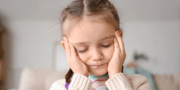 Mädchen hält sich den Kopf