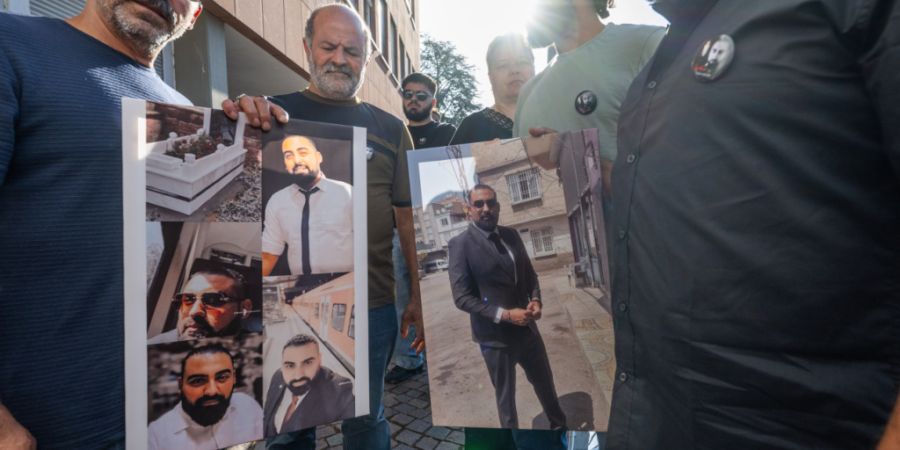 dpatopbilder - Angehörige und Freunde warten mit Fotos des getöteten Zugbegleiters Serkan Calar auf Einlass in das Landgericht. Foto: Boris Roessler/dpa