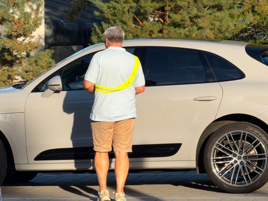 Eine Elterngruppe fängt die Elterntaxis ab und drückt den Fahrerinnen und Fahrern einen Flyer in die Hand.