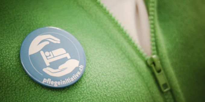 Eine Pflegefachfrau trägt einen Pflegeinitiative-Button. Pflegefachfrau