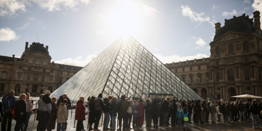 ARCHIV - Besucher stehen vor der Glaspyramide im Louvre in einer Schlange. Foto: Thomas Padilla/AP/dpa