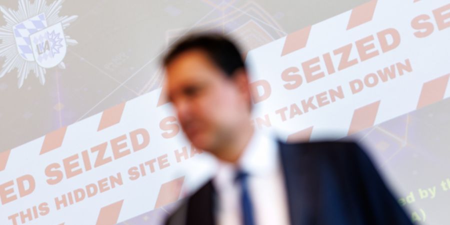 Georg Eisenreich (CSU), Justizminister von Bayern, spricht auf einer Pressekonferenz zur Zerschlagung eines Betrugs-Netzwerks. Hinter ihm ist eine Projektion mit der Aufschrift «Seized ...