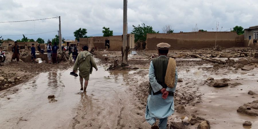 Menschen in der Nähe ihrer beschädigten Häuser nach Überschwemmungen in der nordafghanischen Provinz Baghlan.