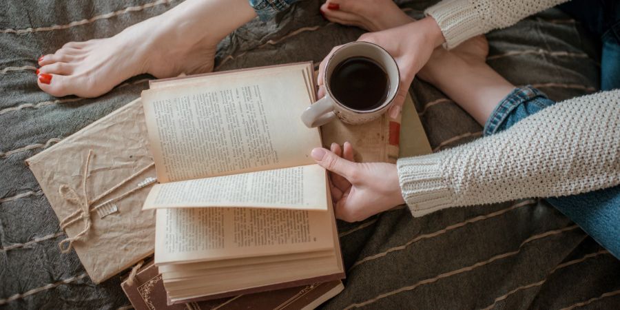 Frau liest Buch und trinkt Kaffee