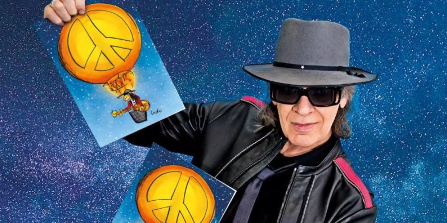 Udo Lindenberg hält Exemplare der Weihnachtskarte in den Händen, die der Sänger und Künstler dieses Jahr für Unicef entworfen hat. Foto: Tine Acke/UNICEF/dpa