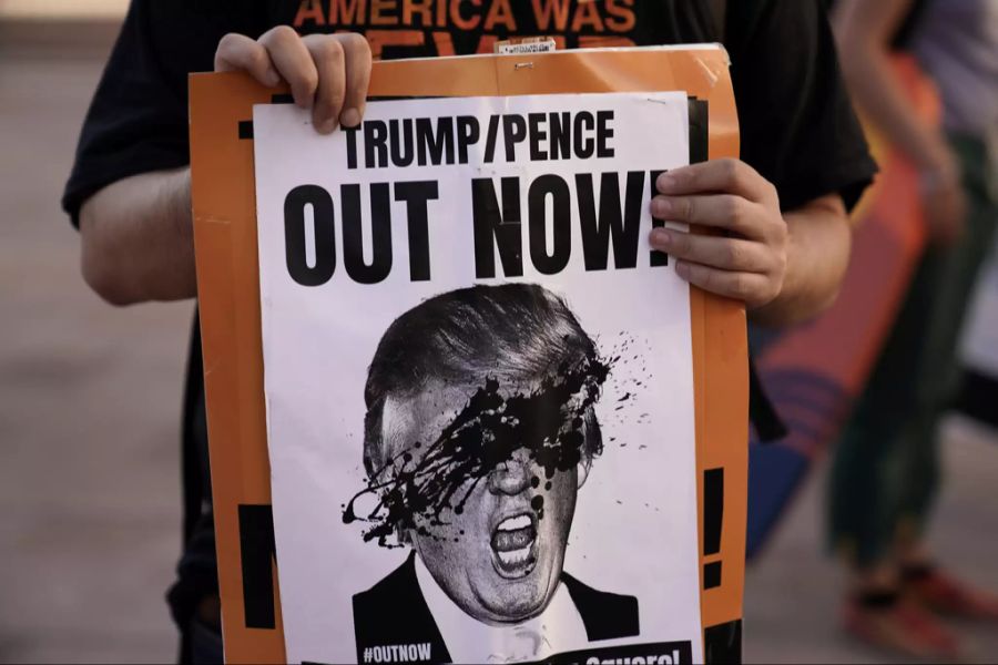 Ein Anhänger von Joe Biden zeigt ein Schild mit dem Gesicht von Donald Trump und der Überschrift «Trump/Pence Out Now».